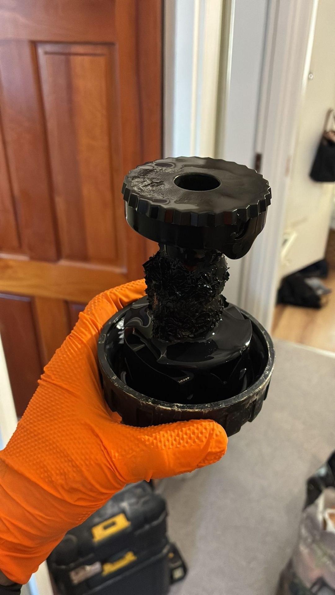 Gloved plumber's hand holding a metal pipe fitting before installation