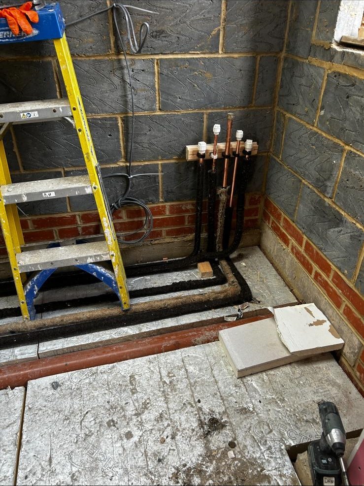 New boiler installation in progress with copper pipework and floorboards lifted